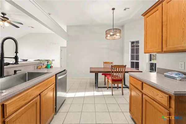 a kitchen with stainless steel appliances granite countertop a sink a stove a refrigerator cabinets and a dining table with chairs
