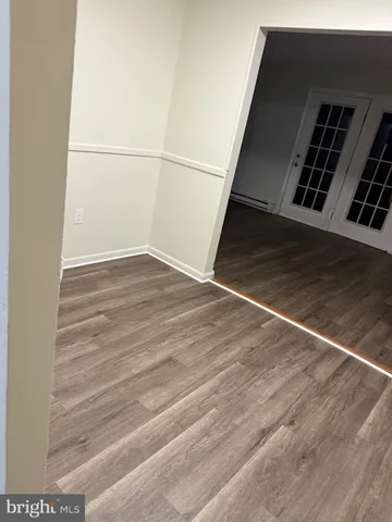 a view of an empty room with wooden floor and windows