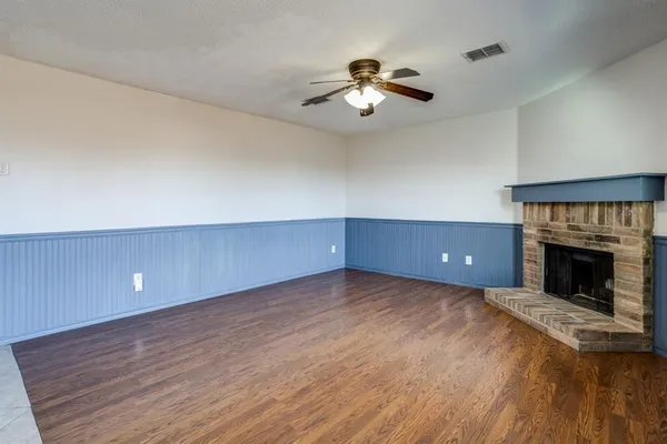 a view of empty room with wooden floor and fireplace