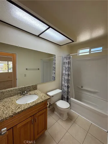a bathroom with a granite countertop sink a toilet a mirror and shower