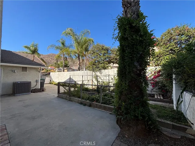a backyard of a house with table and chairs plants and large trees