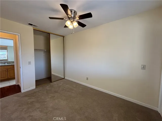 an empty room with closet and a chandelier fan