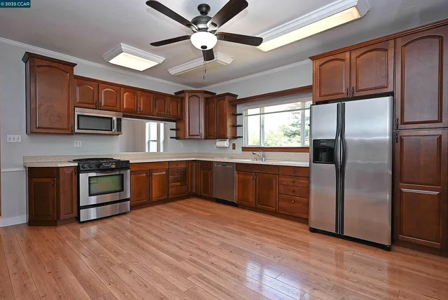 a kitchen with stainless steel appliances kitchen island granite countertop a refrigerator a sink dishwasher a stove and a microwave oven with cabinets