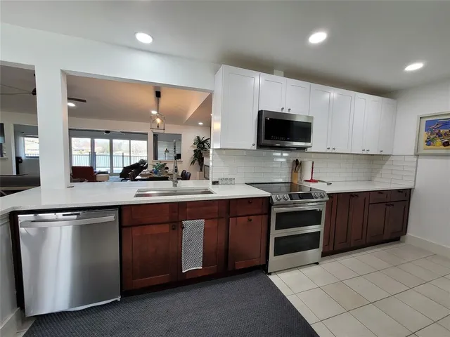 a large kitchen with lots of counter space a sink a window and stainless steel appliances