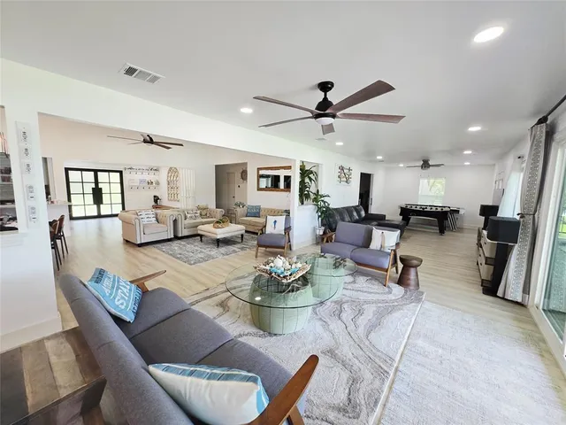 a living room with furniture kitchen view and a wooden floor