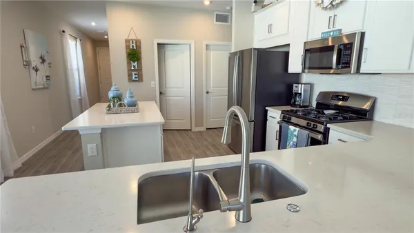 a kitchen with stainless steel appliances kitchen island granite countertop a sink refrigerator and microwave