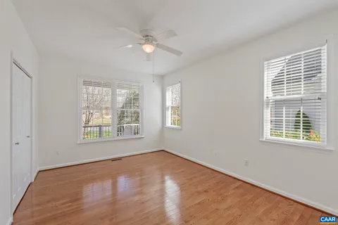 a view of empty room with wooden floor and fan