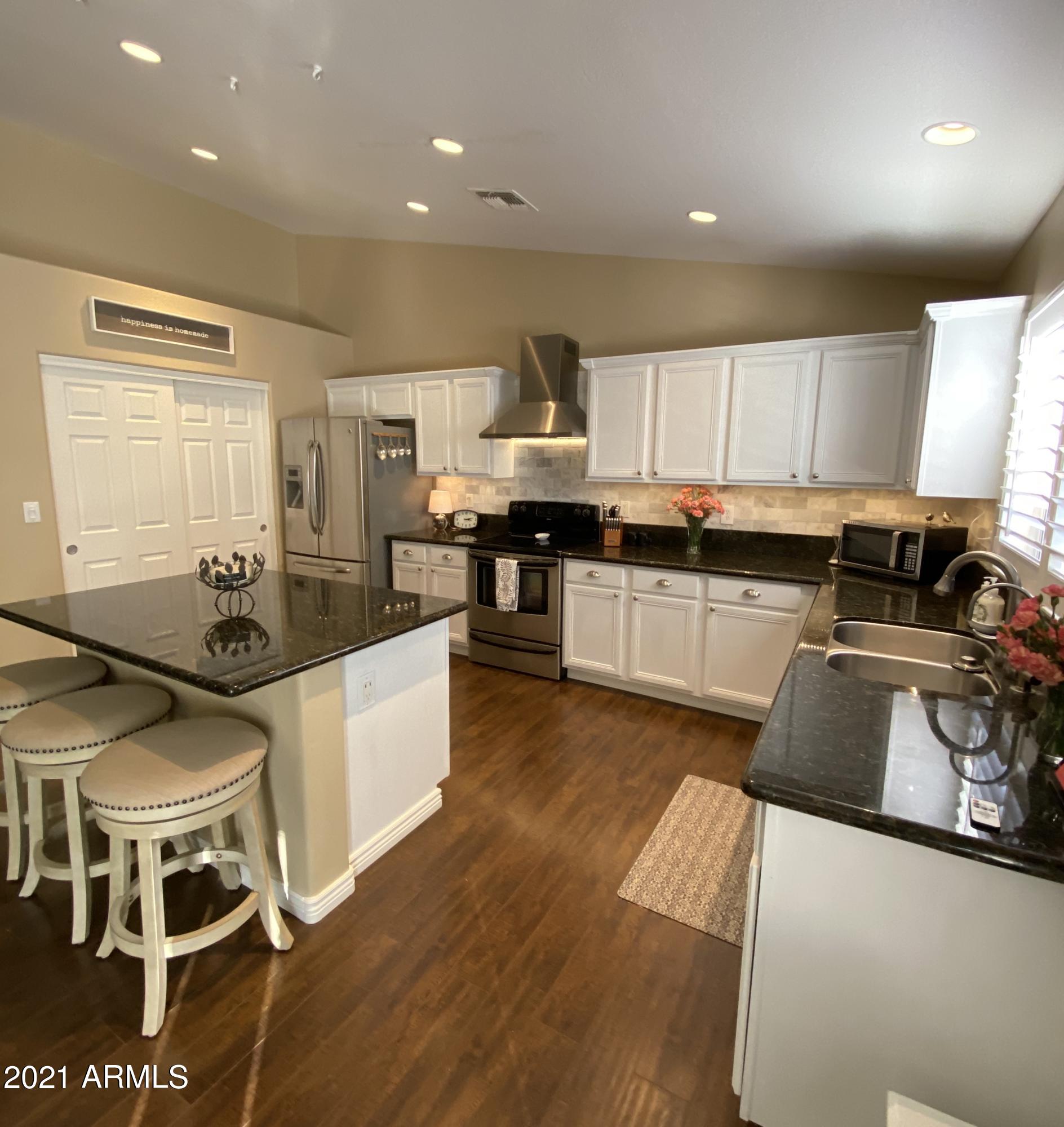 15257 West Hearn Road Surprise, AZ 85379 - Photo 28 of 37 a kitchen with stainless steel appliances kitchen island granite countertop a stove a sink and a refrigerator