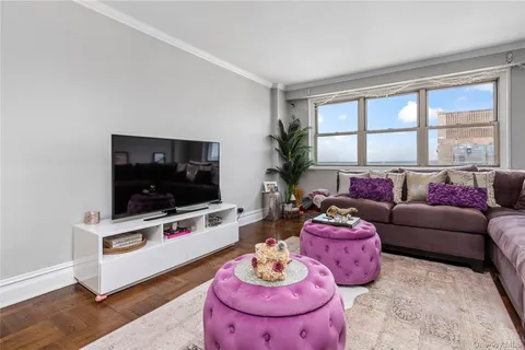 a living room with furniture a flat screen tv and a floor to ceiling window