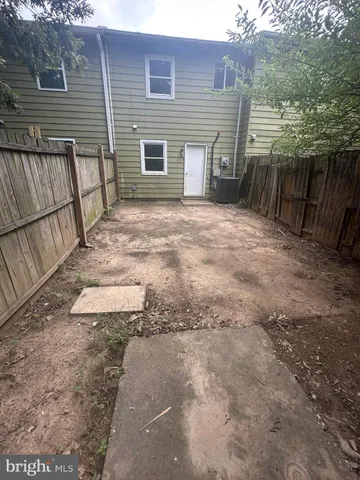 a view of a backyard with wooden fence and large trees