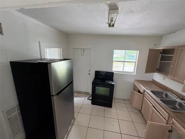 a kitchen with granite countertop a refrigerator and a stove top oven