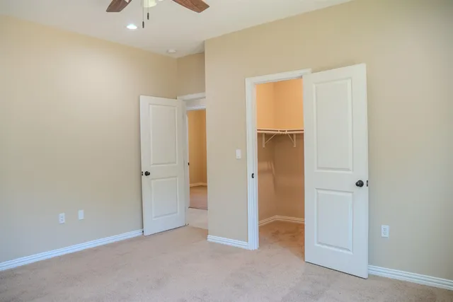 an empty room with closet and a chandelier fan
