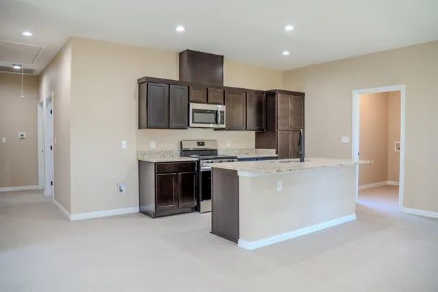 a large kitchen with stainless steel appliances granite countertop a stove a sink and a refrigerator