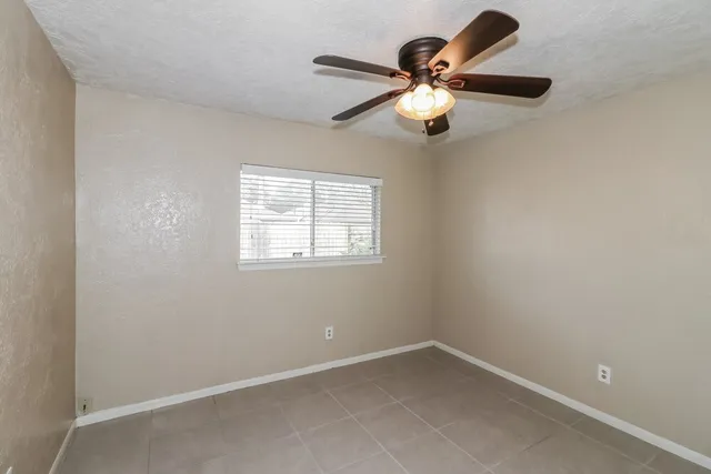 an empty room with a window and a fan