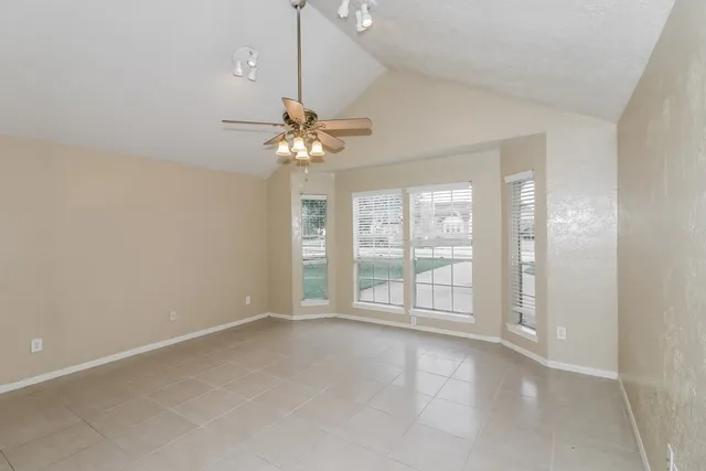 an empty room with chandelier fan and windows