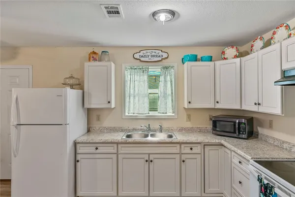 a kitchen with stainless steel appliances granite countertop a sink a refrigerator a stove and white cabinets
