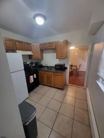 a kitchen with stainless steel appliances a sink a stove a refrigerator a microwave oven and a dining table