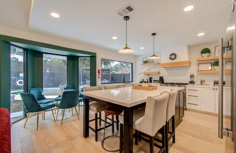a kitchen with stainless steel appliances kitchen island granite countertop a table chairs and a refrigerator