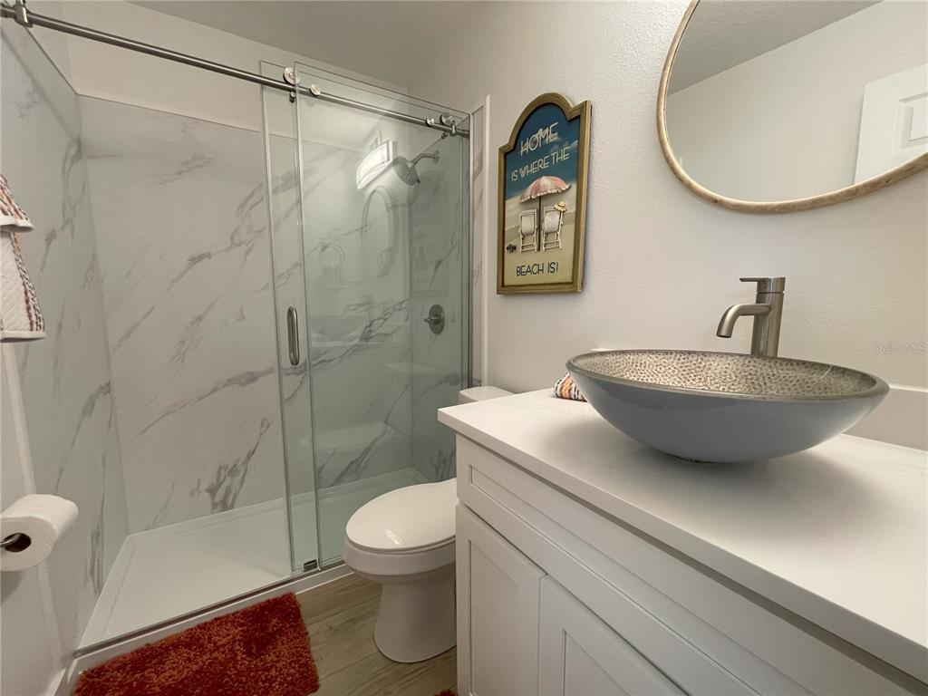 250 Rosery Road Northwest, Unit 329 Largo, FL 33770 - Photo 19 of 27 a bathroom with a sink a mirror a toilet and shower