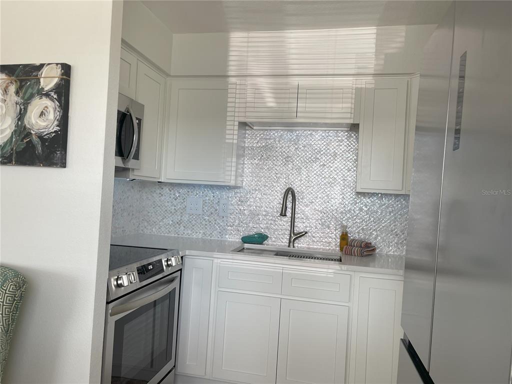 250 Rosery Road Northwest, Unit 329 Largo, FL 33770 - Photo 7 of 27 a kitchen with stainless steel appliances a sink stove and cabinets