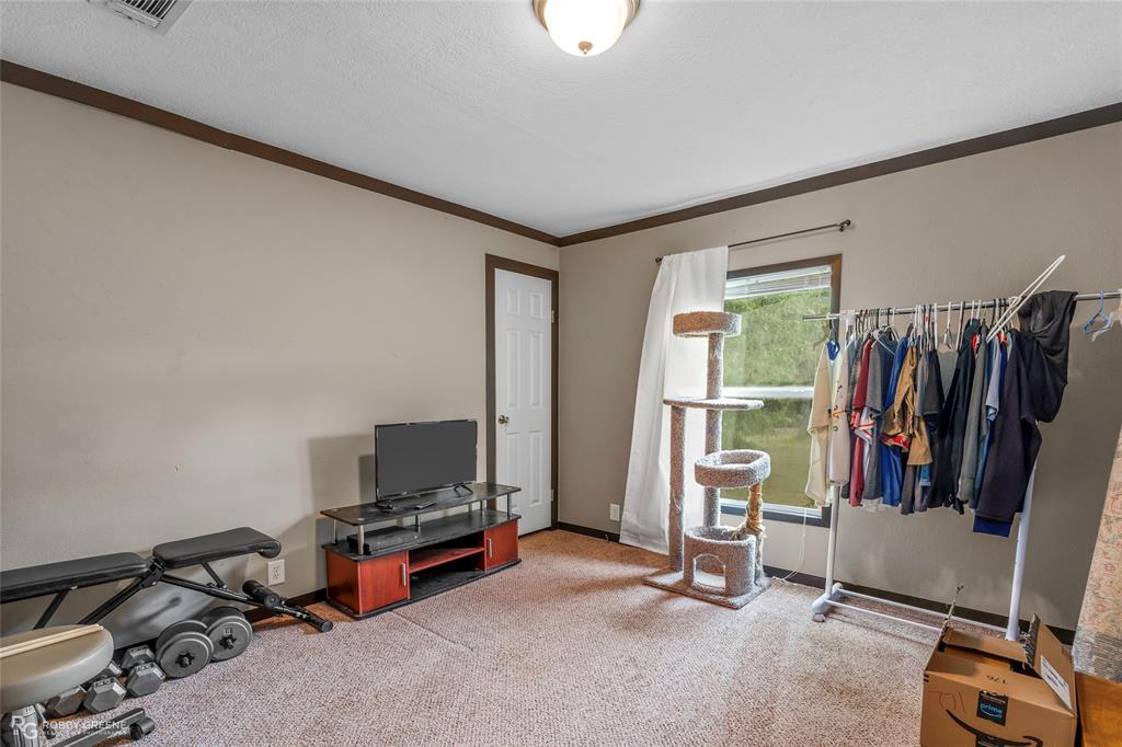 9489 Capps City Road Rodessa, LA 71069 - Photo 20 of 24 Carpeted room featuring a white door, a single window, and neutral wall paint with dark trim