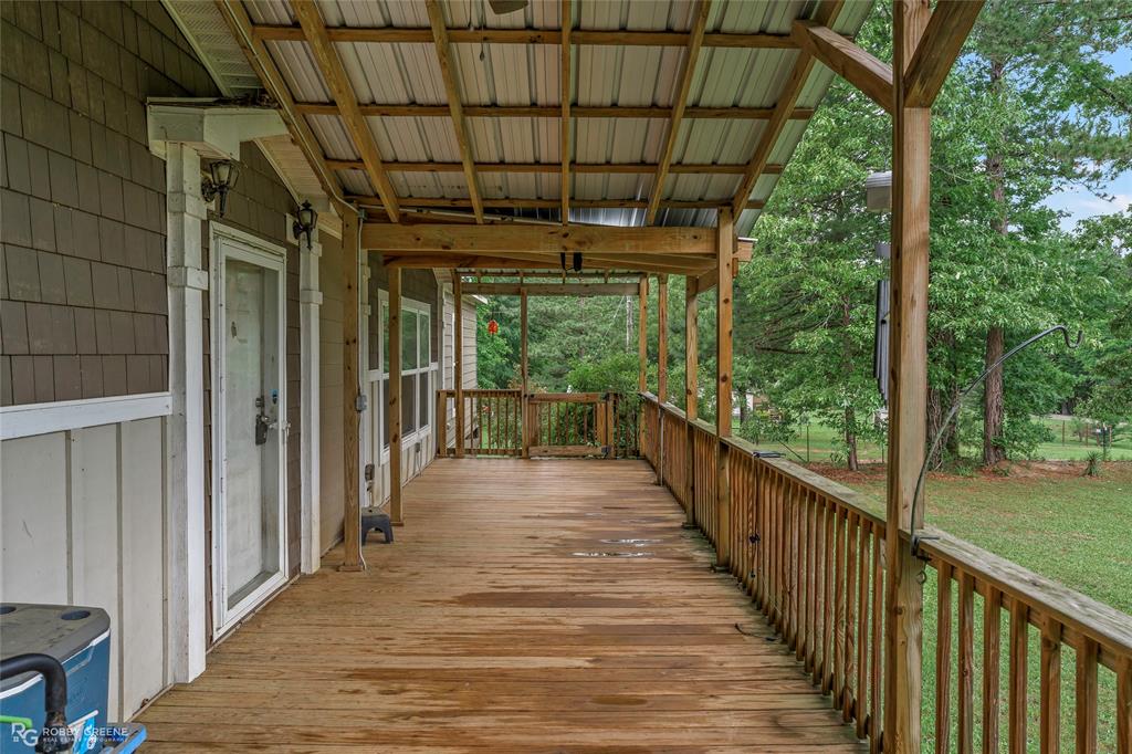 9489 Capps City Road Rodessa, LA 71069 - Photo 2 of 24 Expansive wooden deck with a metal roof overhang