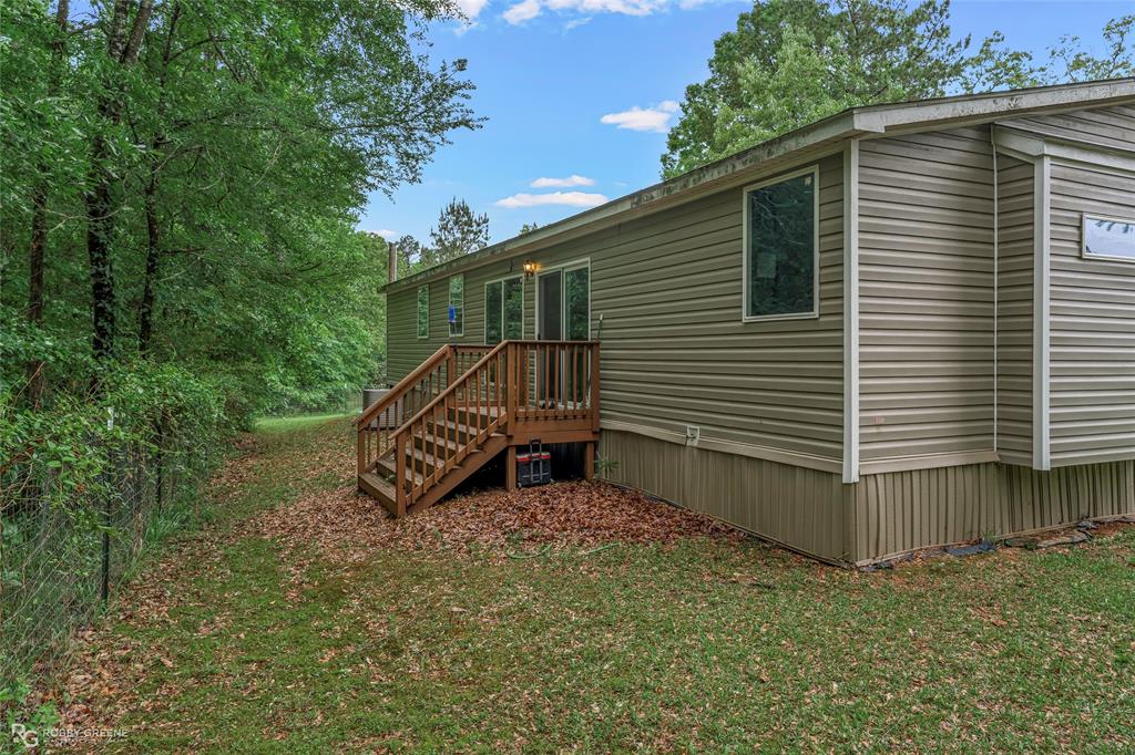 9489 Capps City Road Rodessa, LA 71069 - Photo 21 of 24 Exterior siding with multiple windows and a wooden deck featuring a staircase