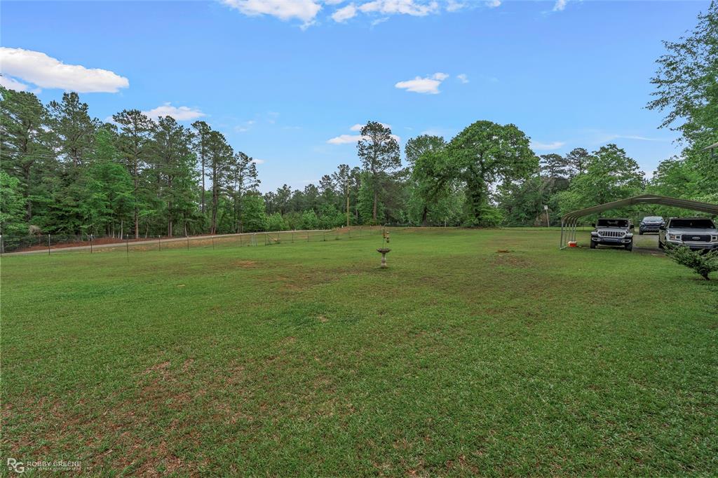 9489 Capps City Road Rodessa, LA 71069 - Photo 22 of 24 Expansive green space featuring a bird bath, partial fencing, and mature trees