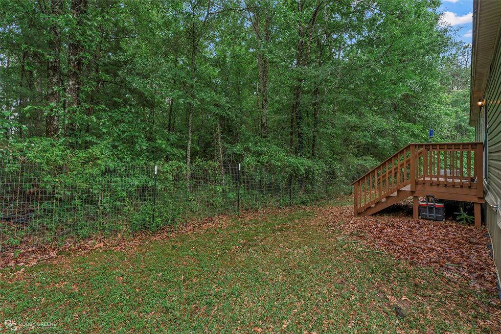9489 Capps City Road Rodessa, LA 71069 - Photo 23 of 24 Wood deck with coordinating wood railings and stairs leading to a partially grassed lawn