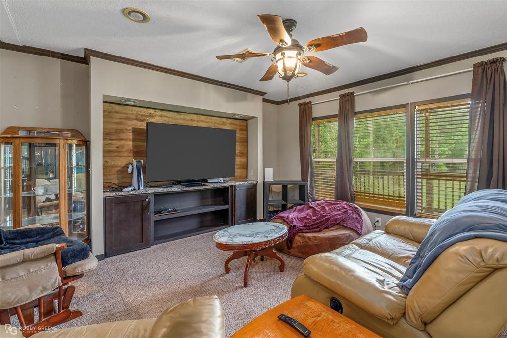 9489 Capps City Road Rodessa, LA 71069 - Photo 4 of 24 Living area featuring a built-in media console with a wood-panel accent wall, recessed lighting, and a ceiling fan