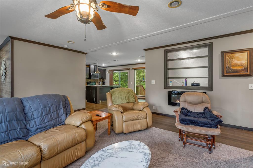 9489 Capps City Road Rodessa, LA 71069 - Photo 6 of 24 Living area featuring a ceiling fan with integrated lighting, wood-finish flooring, and crown molding