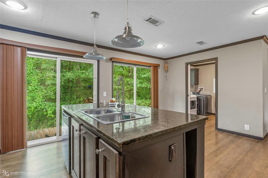 9489 Capps City Road Rodessa, LA 71069 - Photo 7 of 24 Kitchen island with a granite-style countertop, dual stainless steel sinks, and a gooseneck faucet