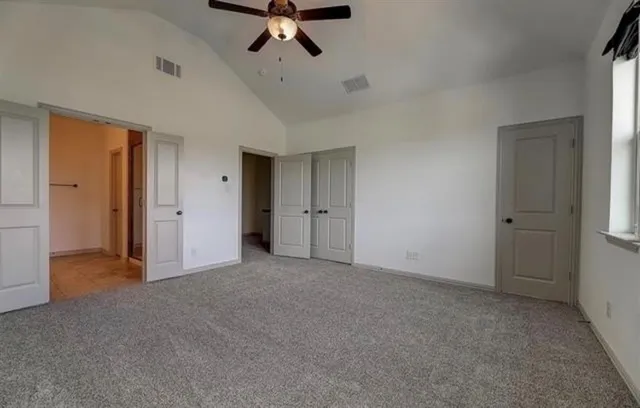 an empty room with ceiling fan and window
