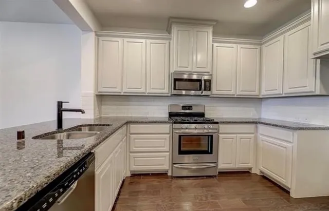 a kitchen with stainless steel appliances granite countertop a stove a sink and a microwave