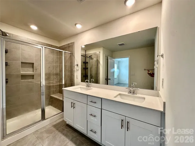 a bathroom with a double vanity sink mirror and shower