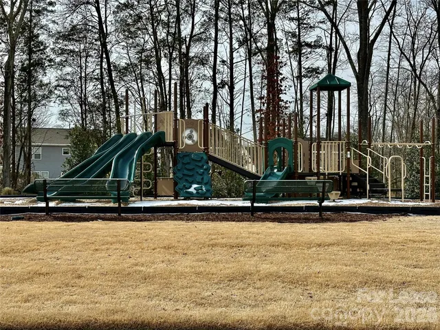 a view of swimming pool with large trees and wooden fence