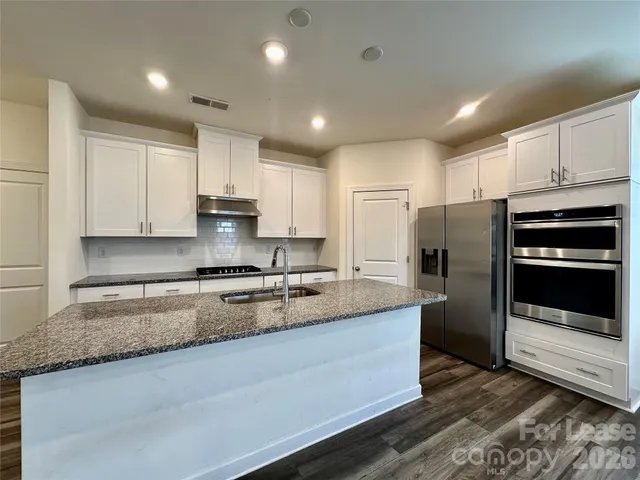 a large kitchen with granite countertop a large counter top stainless steel appliances and cabinets