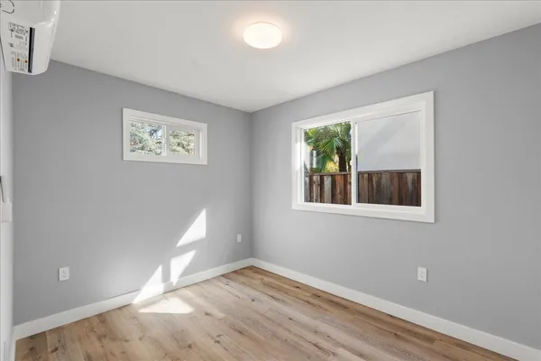a view of an empty room with wooden floor and a window