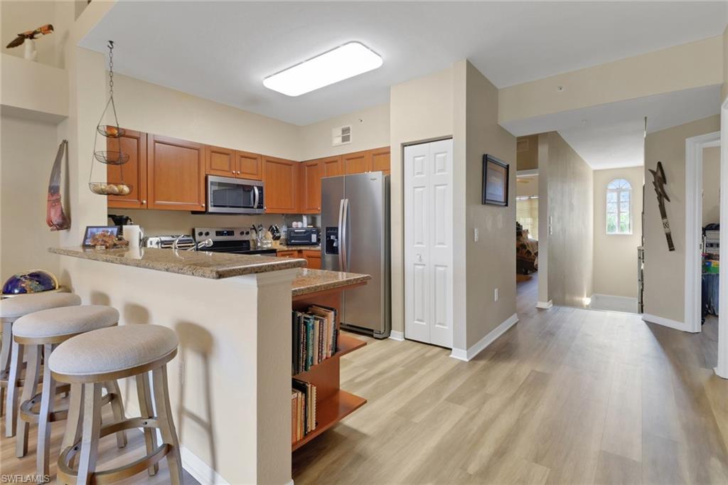 20121 Estero Gardens Circle, Unit 203 Estero, FL 33928 - Photo 4 of 40 a kitchen with stainless steel appliances a refrigerator a stove a sink dishwasher and a refrigerator with wooden floor