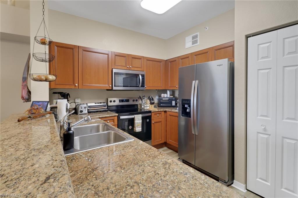 20121 Estero Gardens Circle, Unit 203 Estero, FL 33928 - Photo 8 of 40 a kitchen with stainless steel appliances granite countertop a refrigerator stove and sink