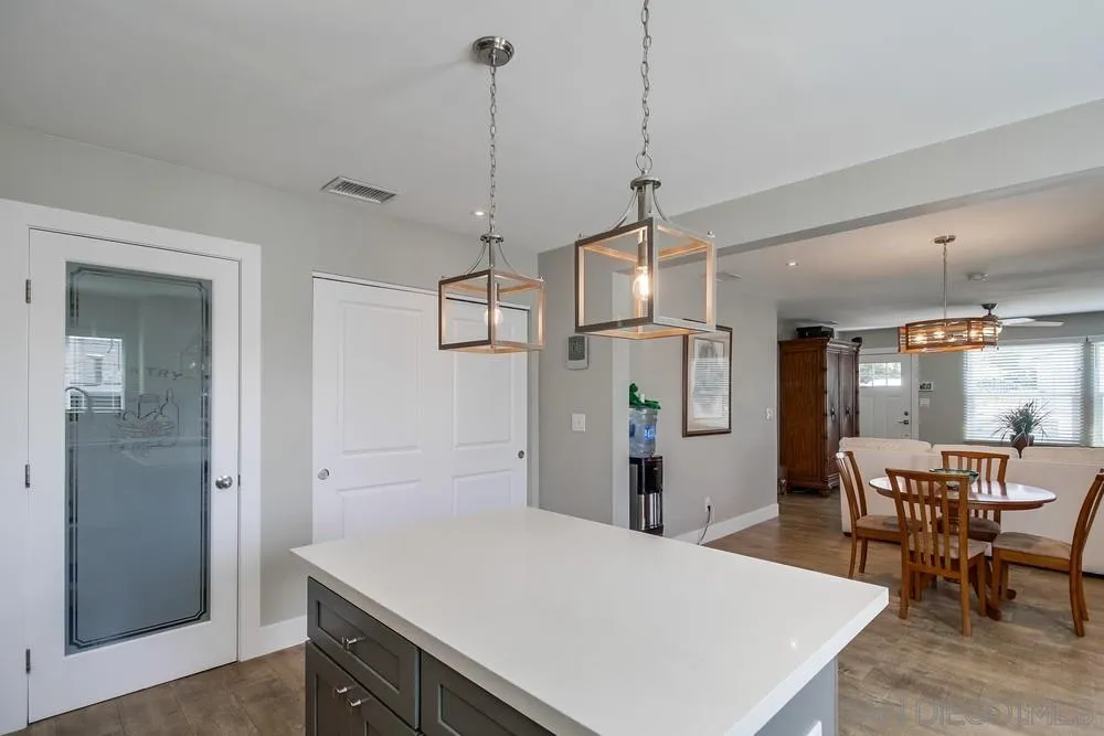 730 Pidgeon Street San Diego, CA 92114 - Photo 13 of 39 a kitchen with kitchen island a refrigerator a sink dishwasher a dining table and chairs with wooden floor