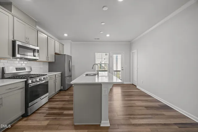 a kitchen with stainless steel appliances granite countertop a stove top oven a sink dishwasher and a refrigerator with wooden floor