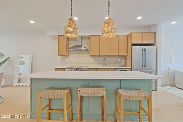 a kitchen with stainless steel appliances granite countertop a stove a sink refrigerator and a dining table with wooden floor