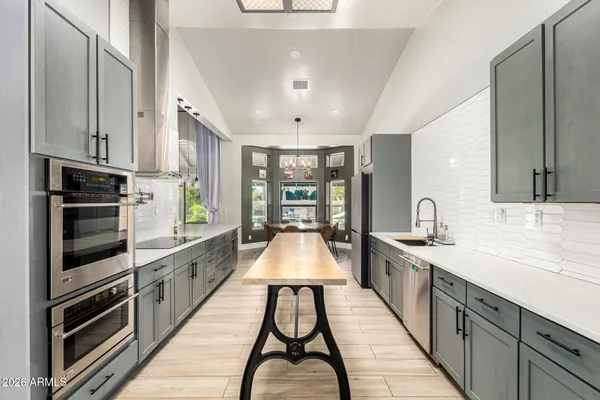 a kitchen with stainless steel appliances kitchen island granite countertop a table chairs in it and wooden floors