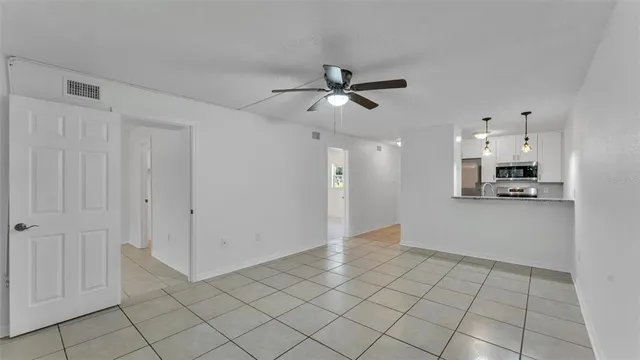 an empty room with chandelier fan and windows