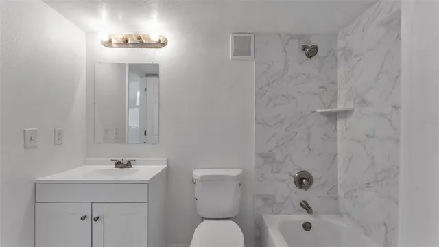 a bathroom with a bathtub shower sink vanity mirror and toilet