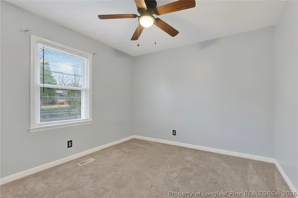 an empty room with a window and a fan