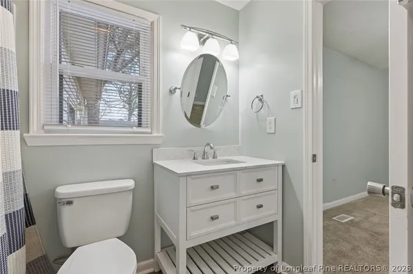 a bathroom with a granite countertop toilet a sink and a mirror