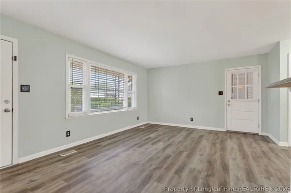 a view of an empty room with wooden floor and a window