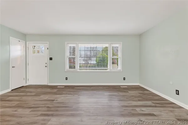 a view of an empty room with wooden floor and a window